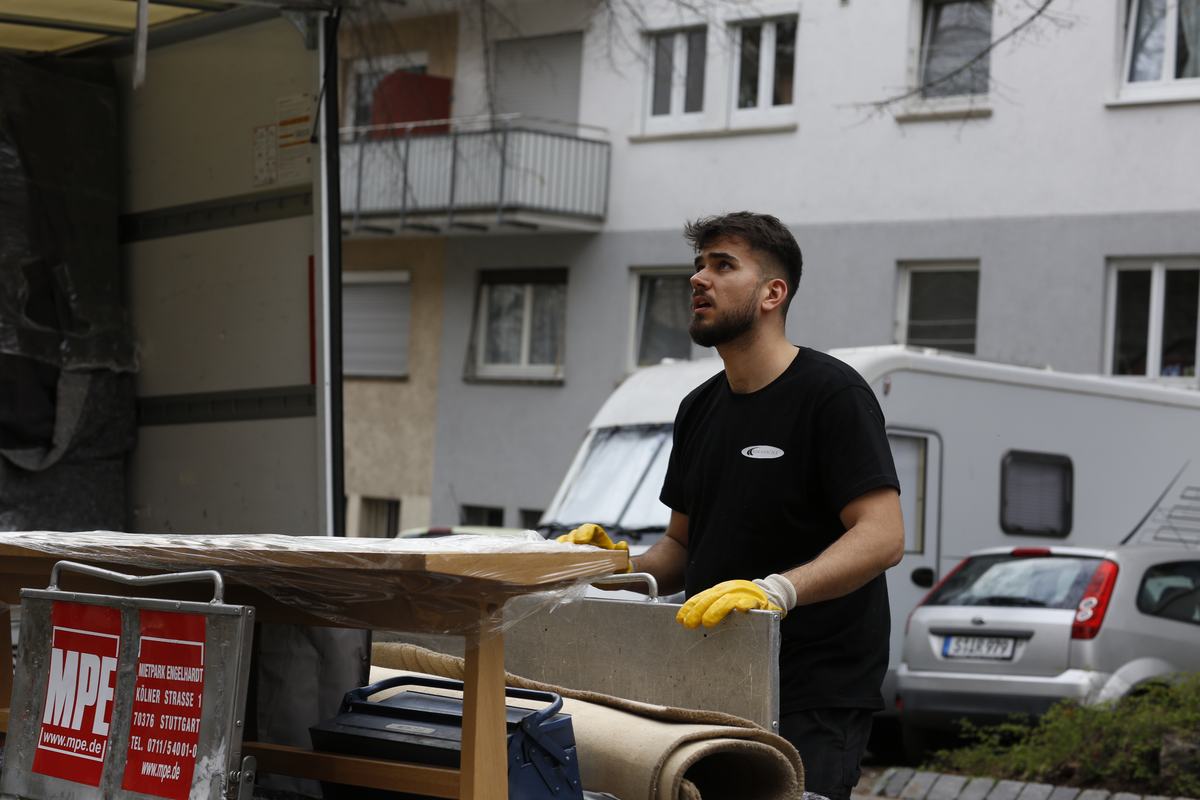 Ein Mitarbeiter sichert einen in Folie verpackten Tisch für den Möbeltransport