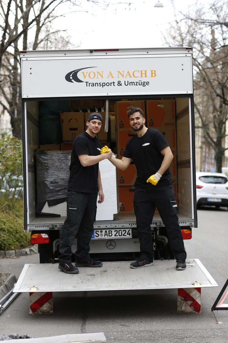 Zwei Mitarbeiter des Umzugsteams von Von A nach B vor dem beladenen Umzugswagen