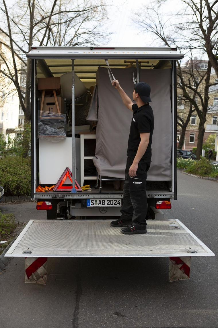 Mitarbeiter von Von A nach B sichern verpackte Möbel im Umzugswagen